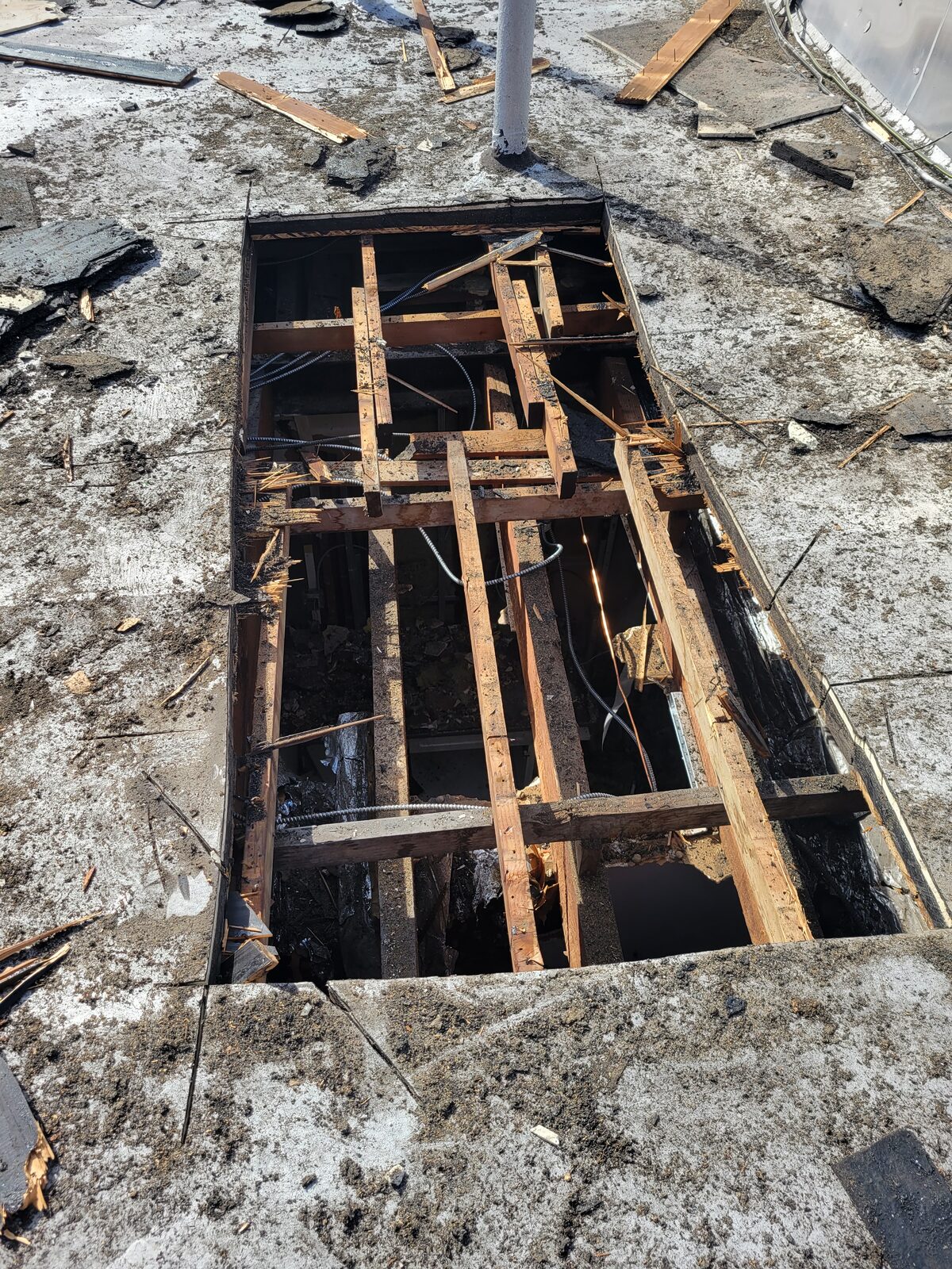 Roof deck opened to expose fire-damaged wood framing during emergency repair, Harlem, Manhattan