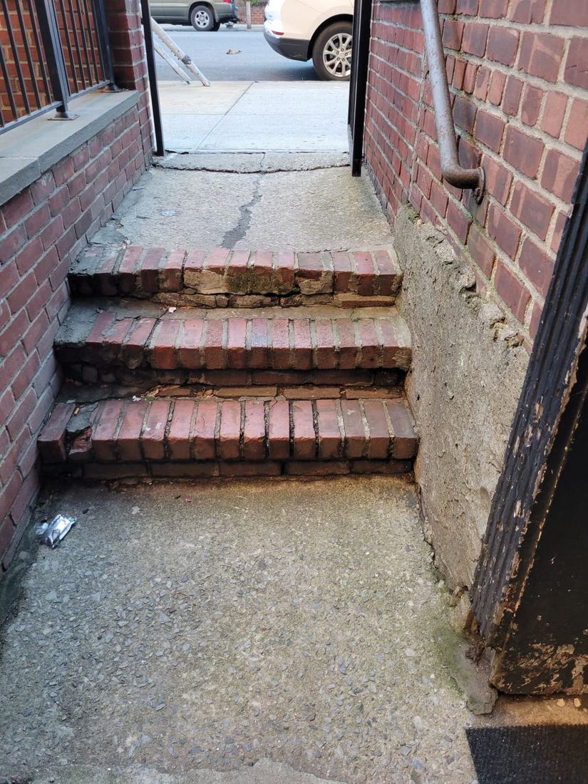 Worn original brick entry steps before restoration