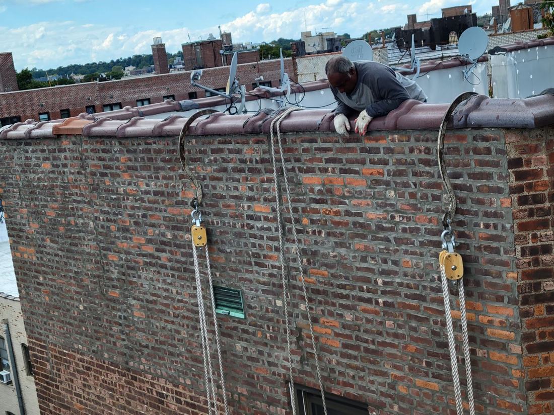 Mason working on rooftop parapet coping