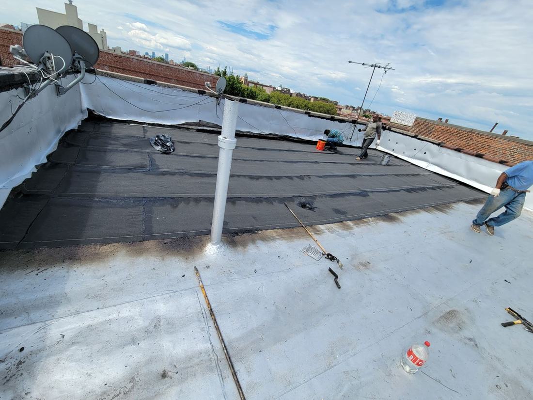 Roofing crew applying seam coating on rooftop